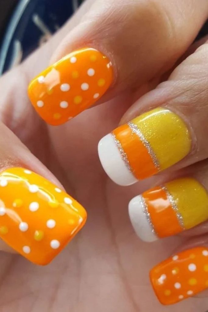Candy corn nails with colorful polka dots.