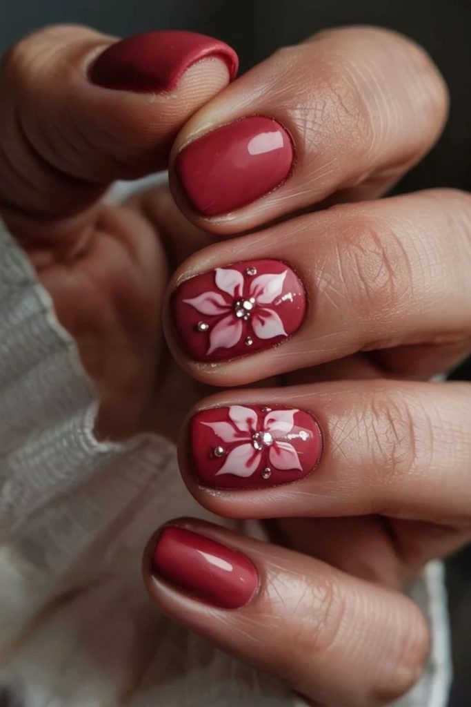 Matte red nails with glossy poinsettia flowers.