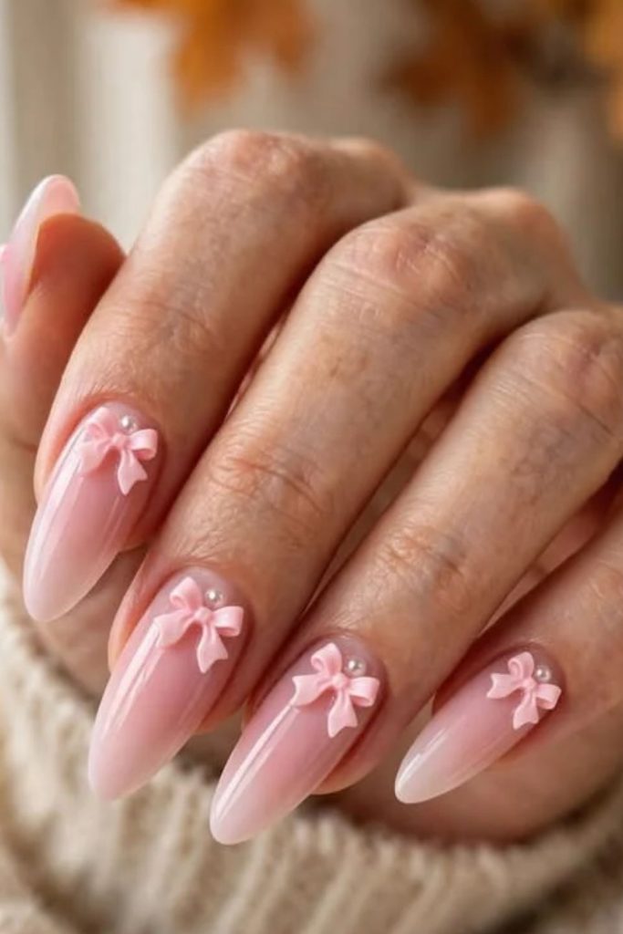 Pink ombre coquette nails with delicate bows.