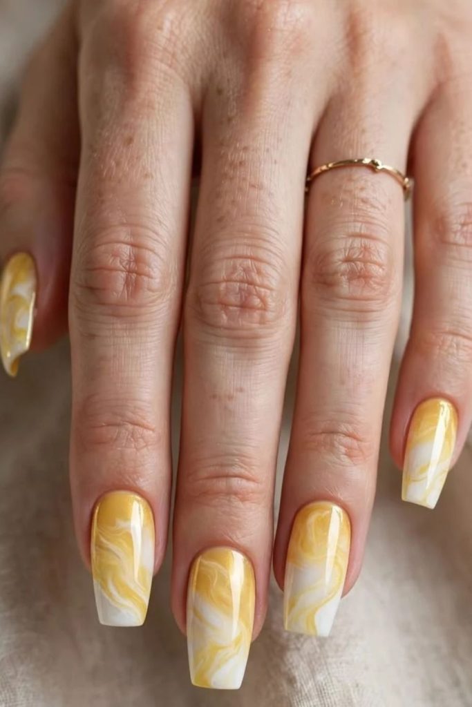 Soft butter yellow marble nails.